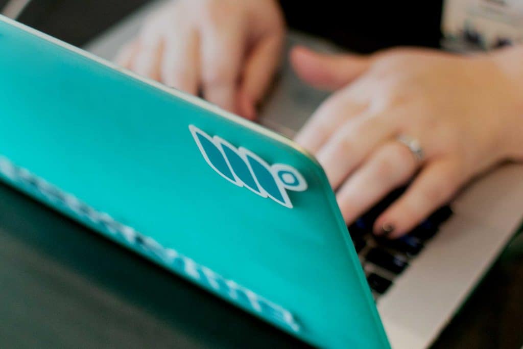 woman's hands typing on a teal computer covered in Mediavine stickers