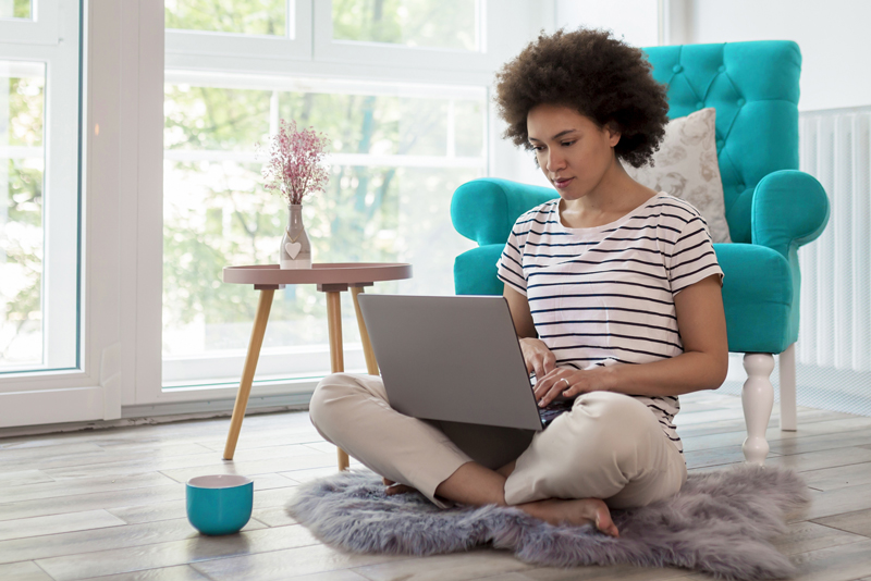 person sitting on floor with laptop in lap