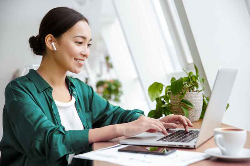woman using laptop wearing earbuds