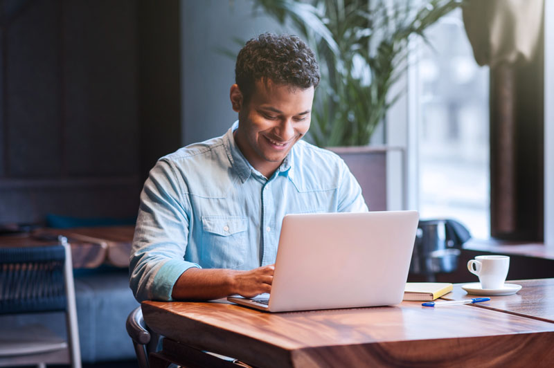 man on laptop sitting in a cafeteria