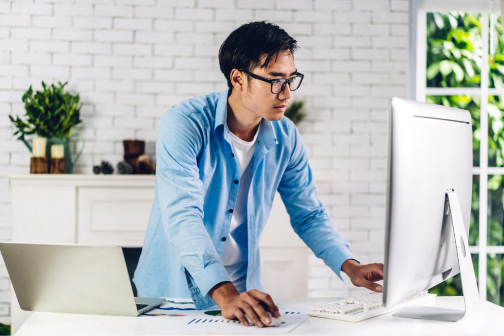 man standing up using a desktop computer